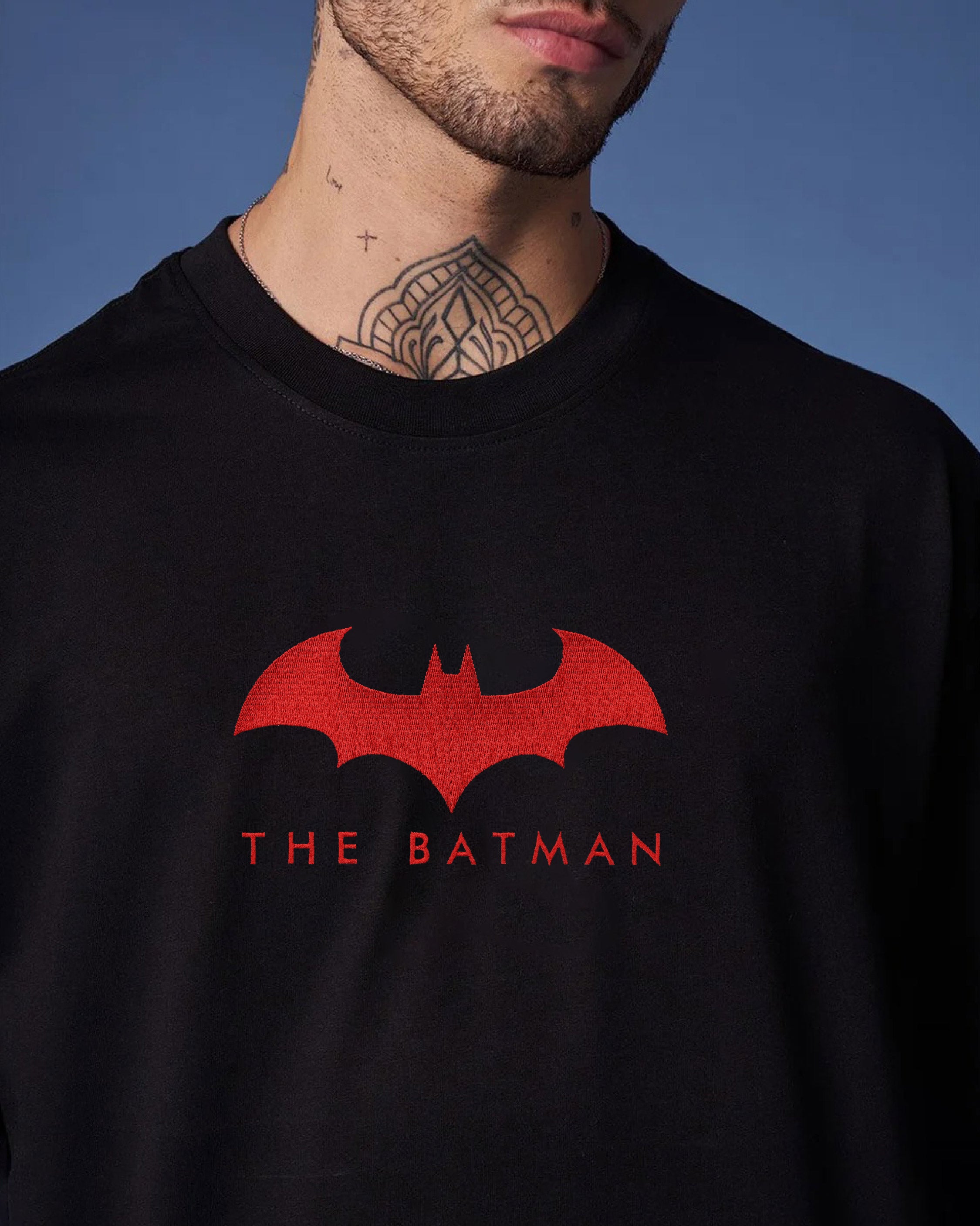 Black sweatshirt with red Batman logo and text against a blue background
