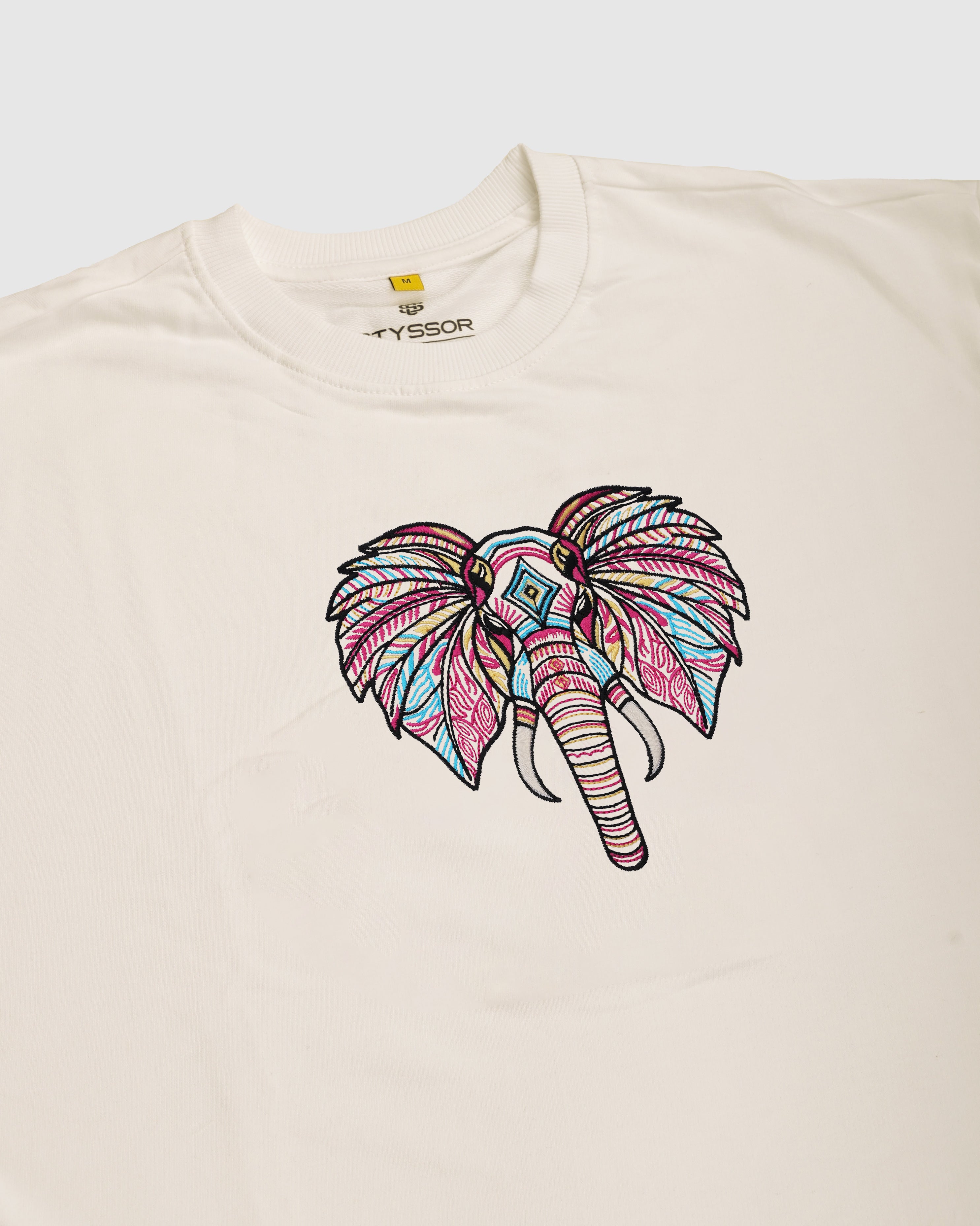 Beige t-shirt with a colorful elephant design on a white background