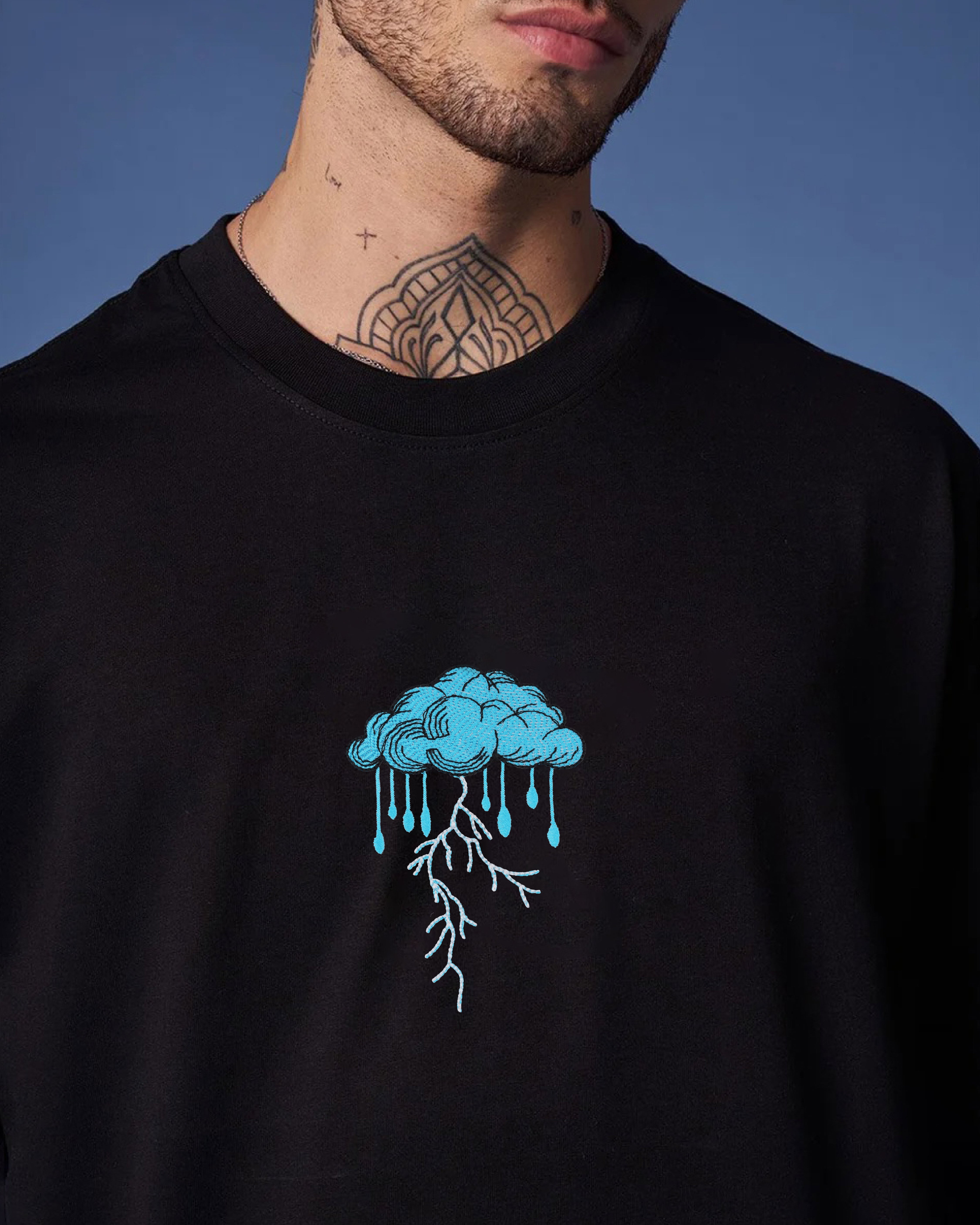 Person wearing a black sweatshirt with a blue cloud design on a blue background