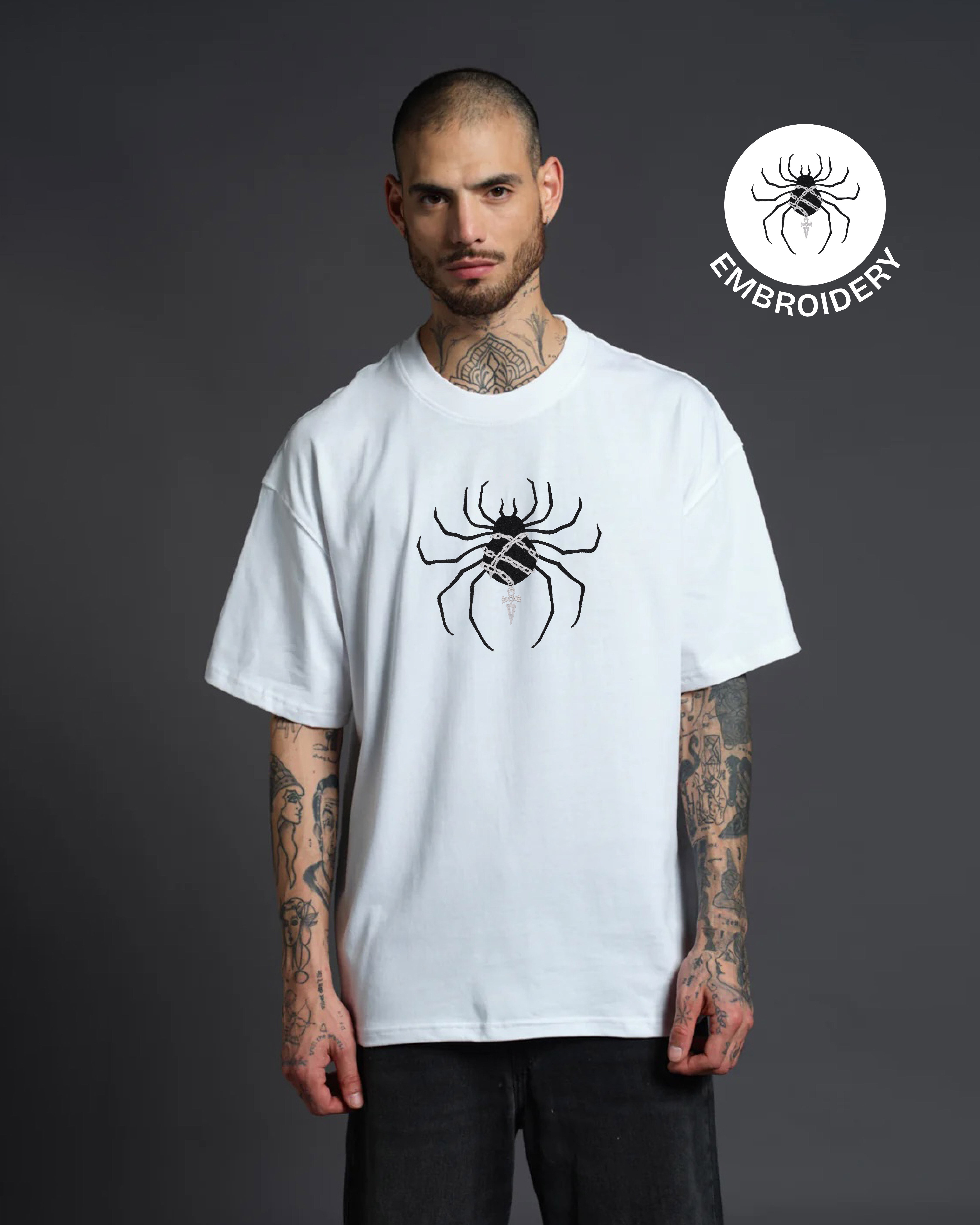 Man wearing a white t-shirt with a spider design on a dark background