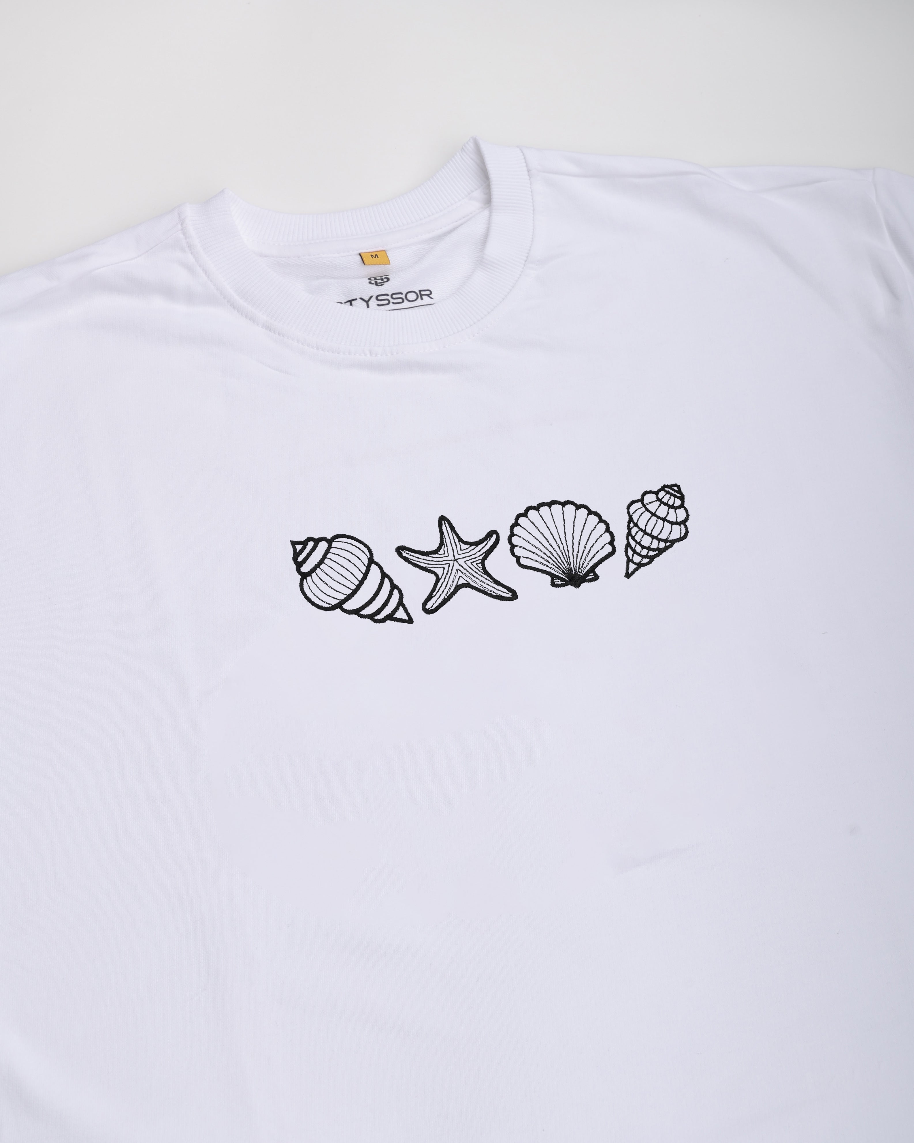 White t-shirt with black shell and starfish designs on a white background