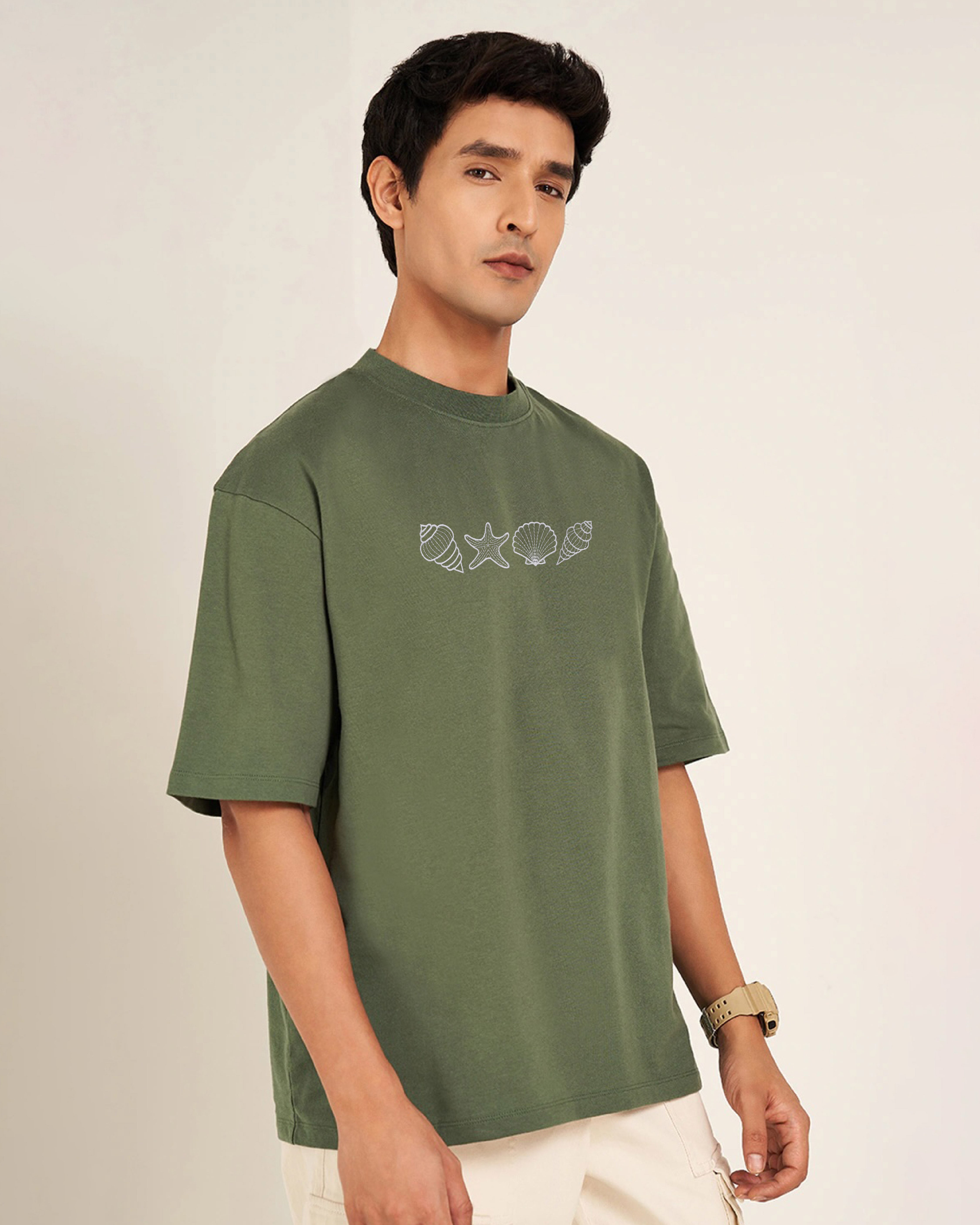 Man wearing a green t-shirt with a embroidery design on a plain background