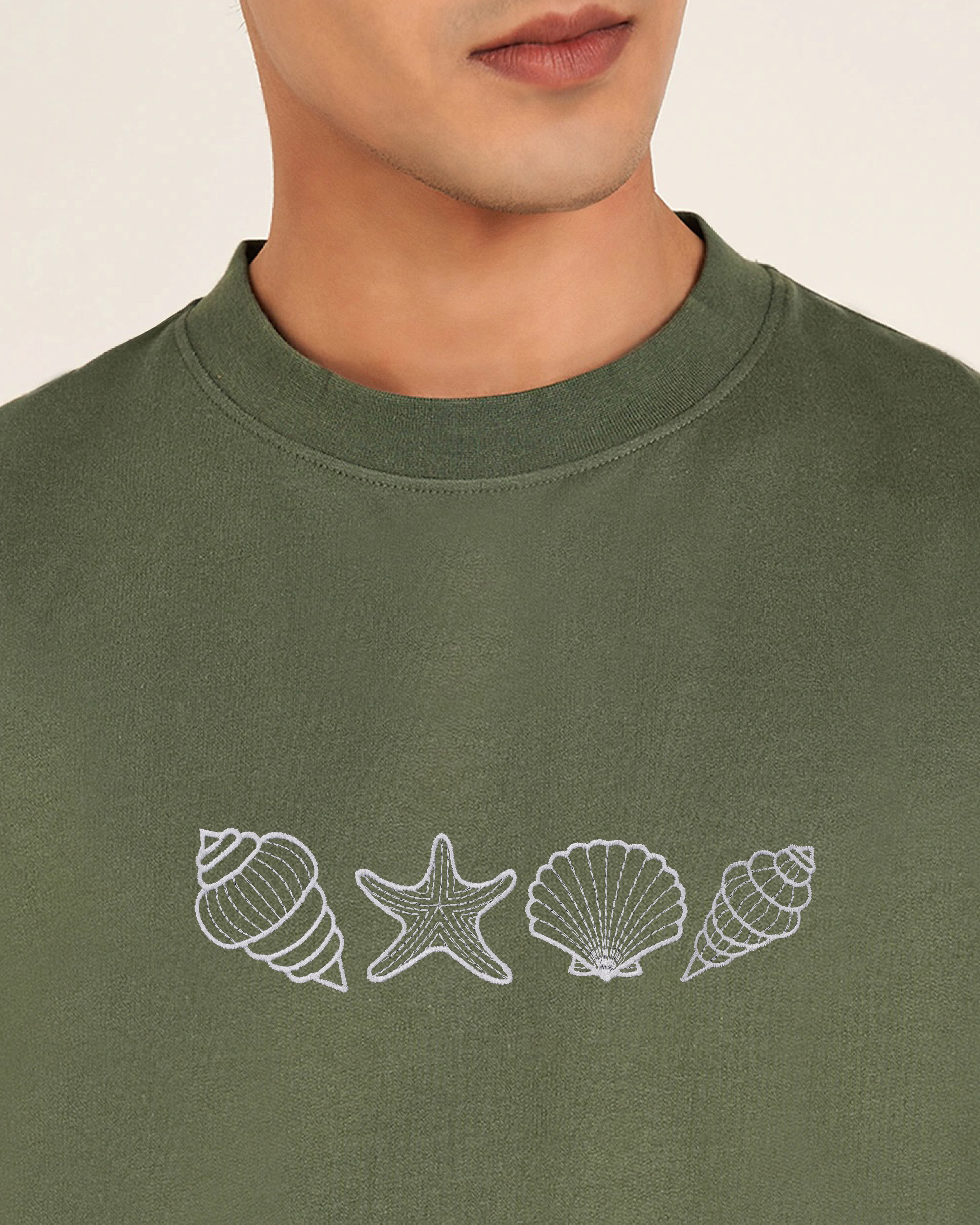 Green sweatshirt with white shell and starfish designs on a plain background
