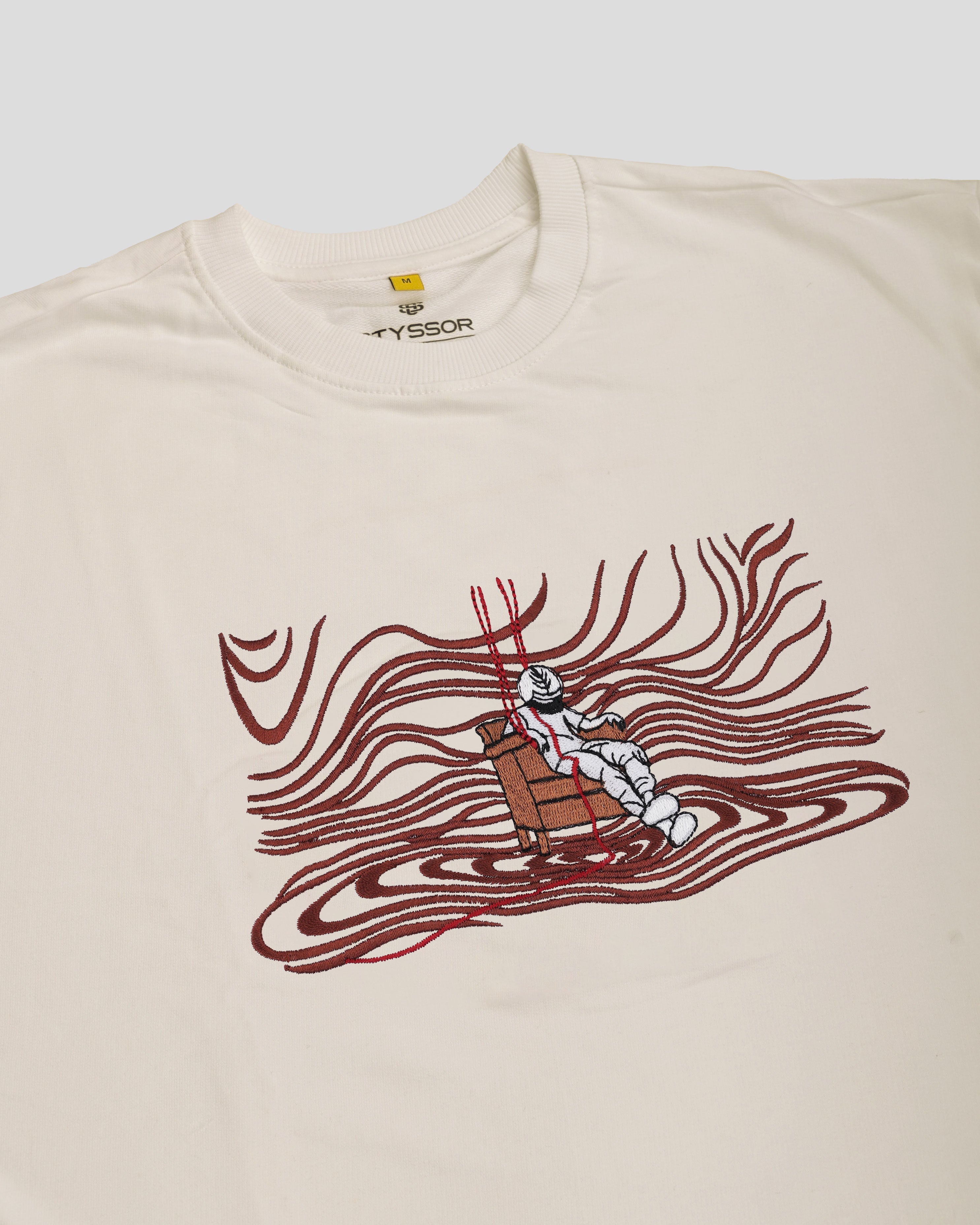 Beige t-shirt with a graphic design of a robot in a red wave on a white background
