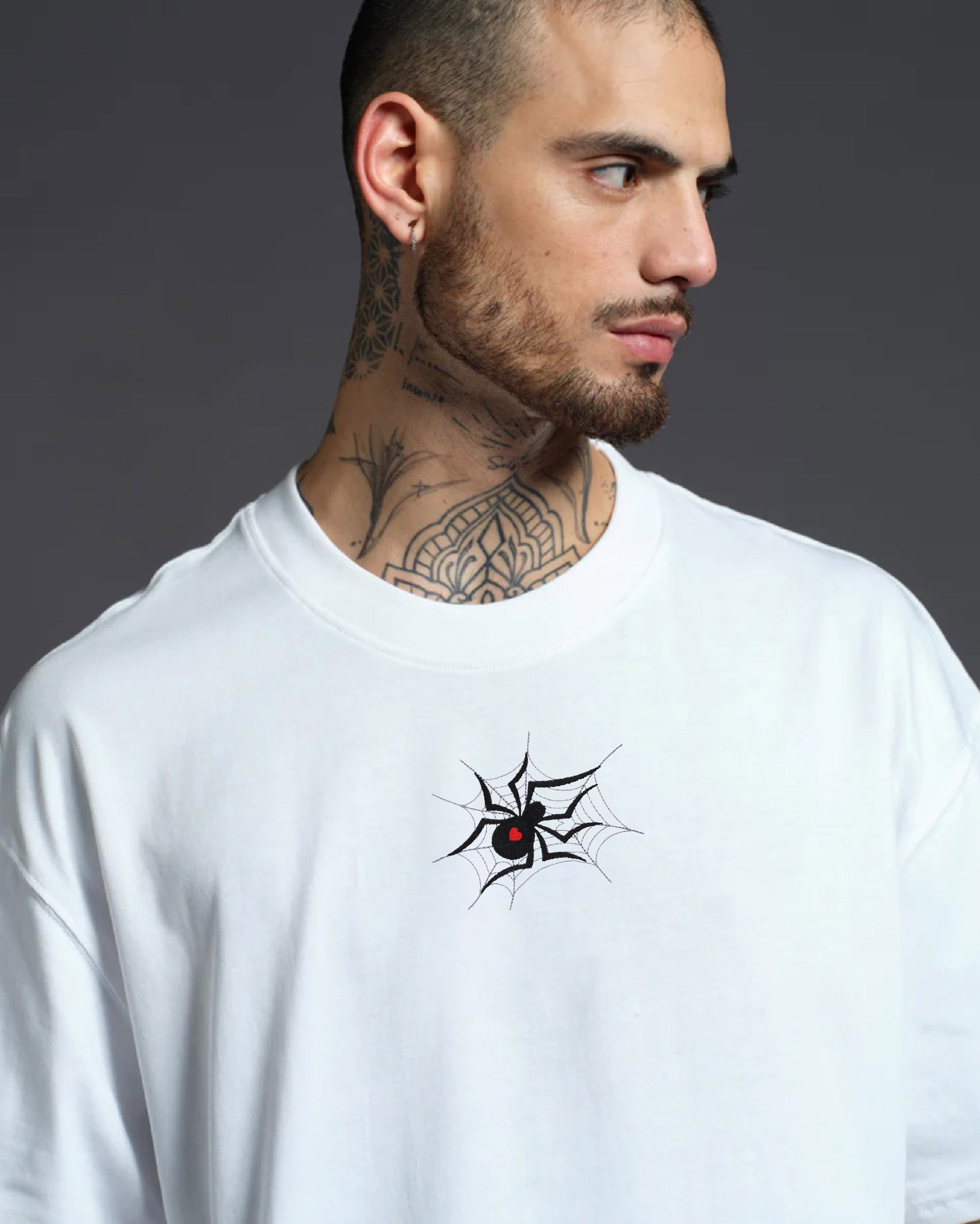 Man wearing a white long-sleeve shirt with a black spider design on a gray background