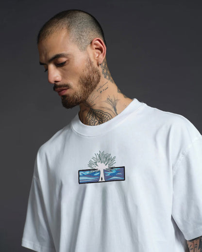 Man wearing a white t-shirt with a graphic design on a dark background