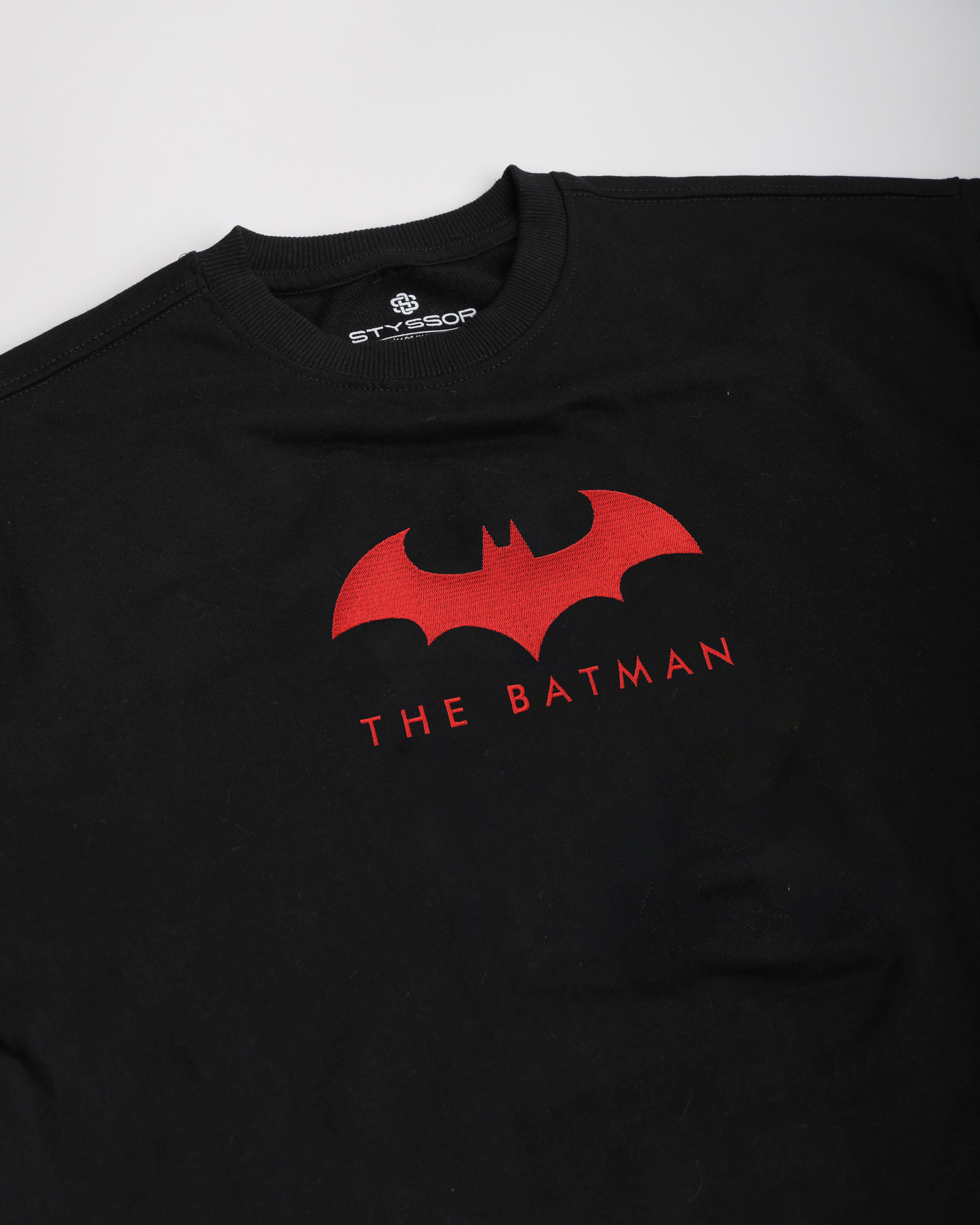 Black t-shirt with red Batman logo and text on a white background