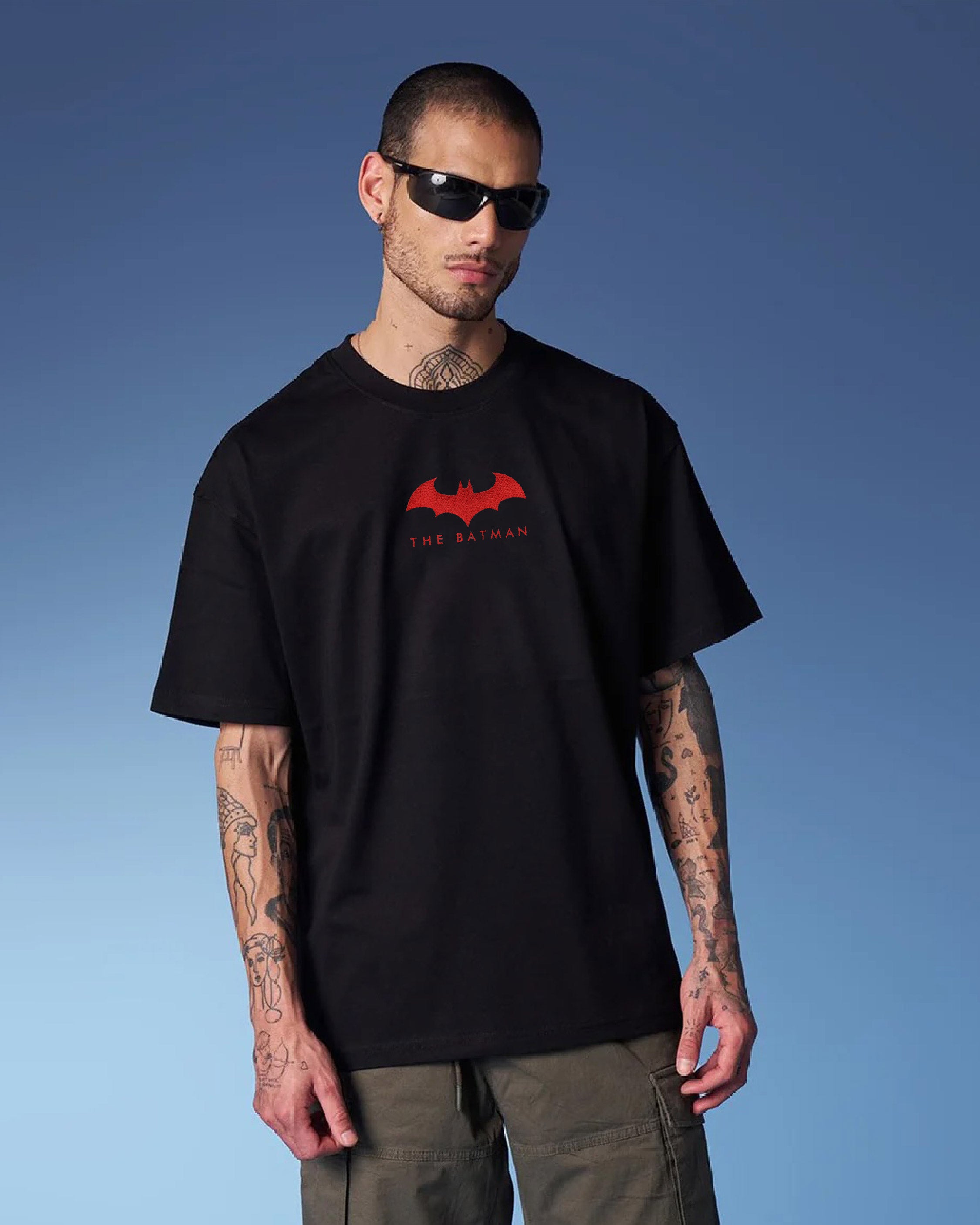 Man wearing a black t-shirt with a red logo against a blue sky