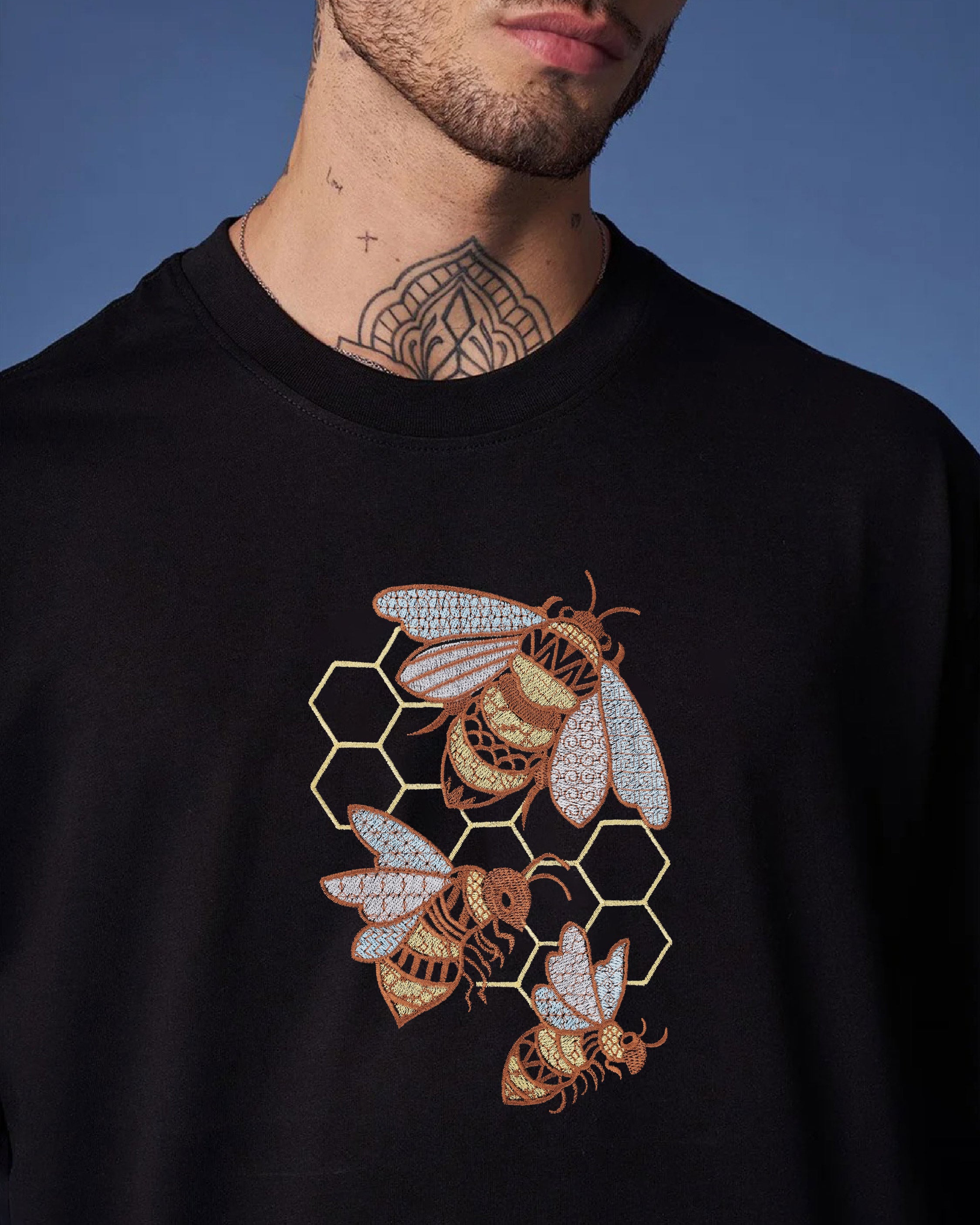 Black sweatshirt with bee and honeycomb design on a blue background