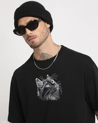 Man wearing a black sweater with a cat graphic and a black beanie and sunglasses on a white background