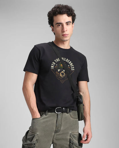 Man wearing a black t-shirt with a bear graphic and text, standing against a gray background