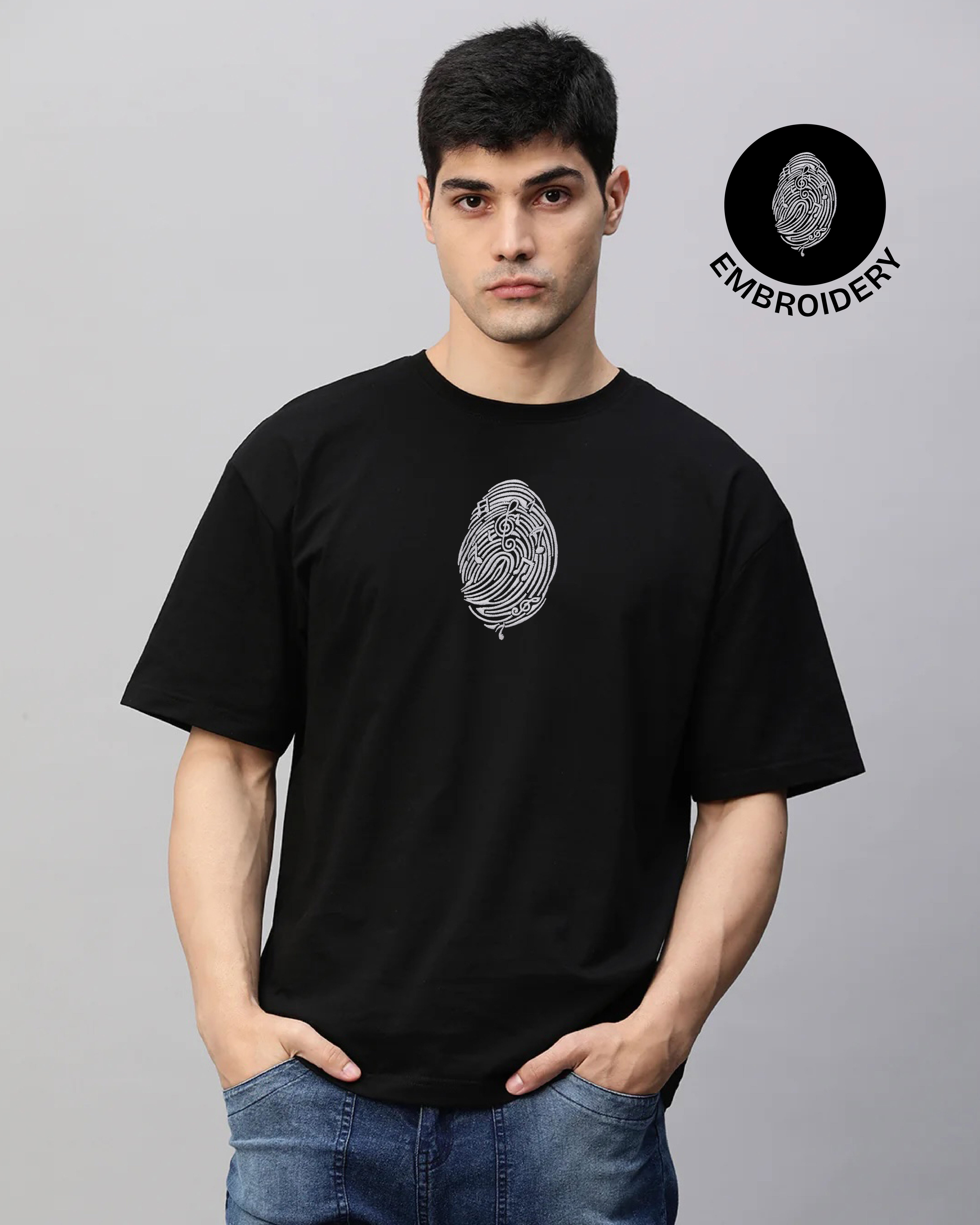 Man wearing a black t-shirt with an embroidered design on a gray background