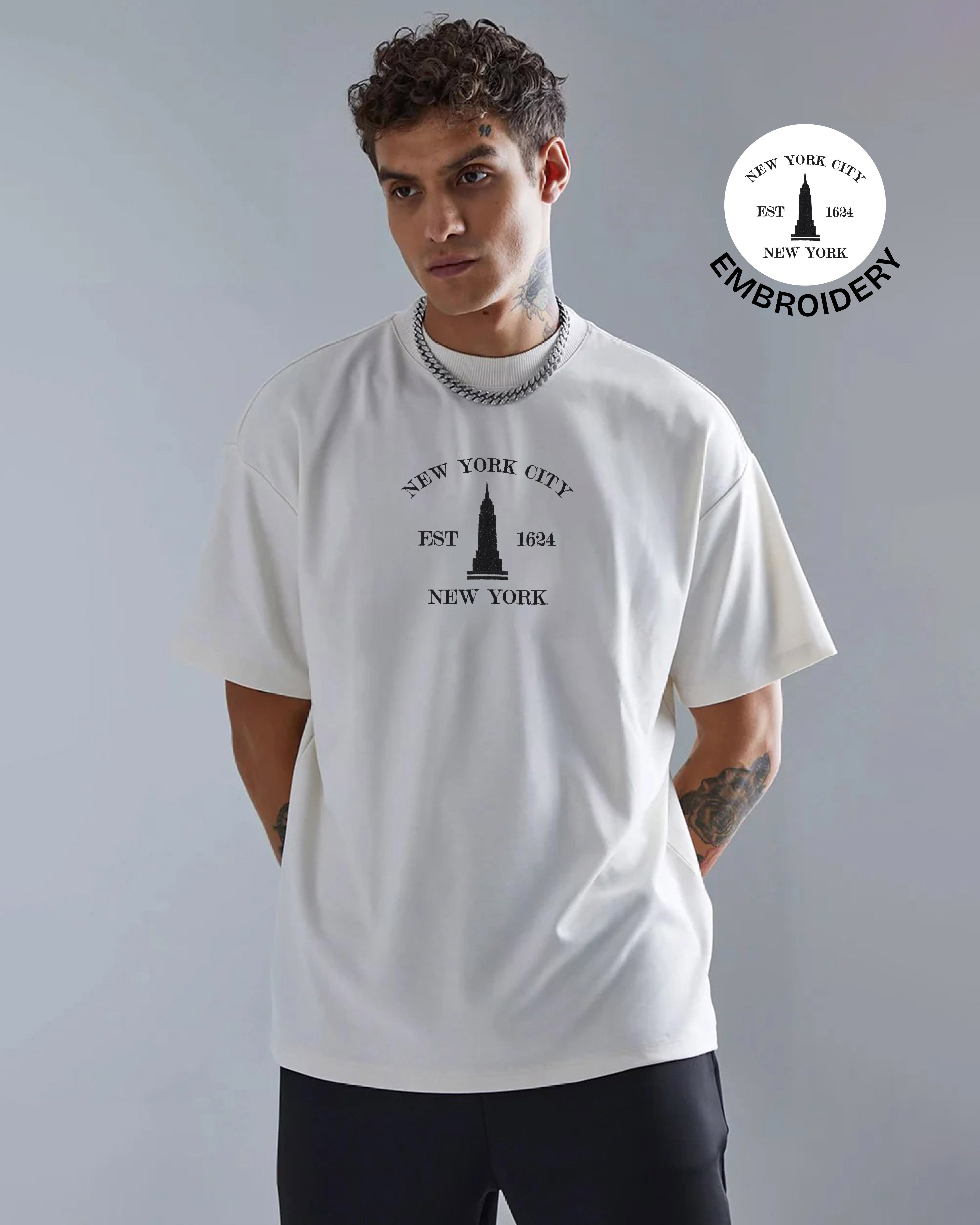 Man wearing a white t-shirt with New York City design, standing against a gray background.