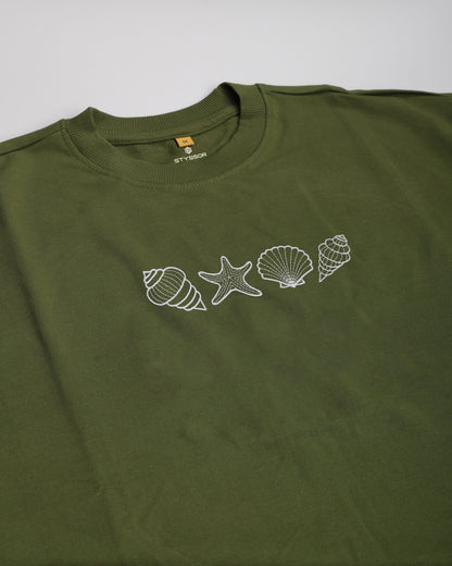 Green t-shirt with white shell and starfish designs on a light gray background