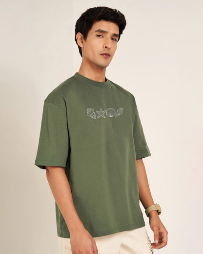 Man wearing a green t-shirt with a embroidery design on a plain background