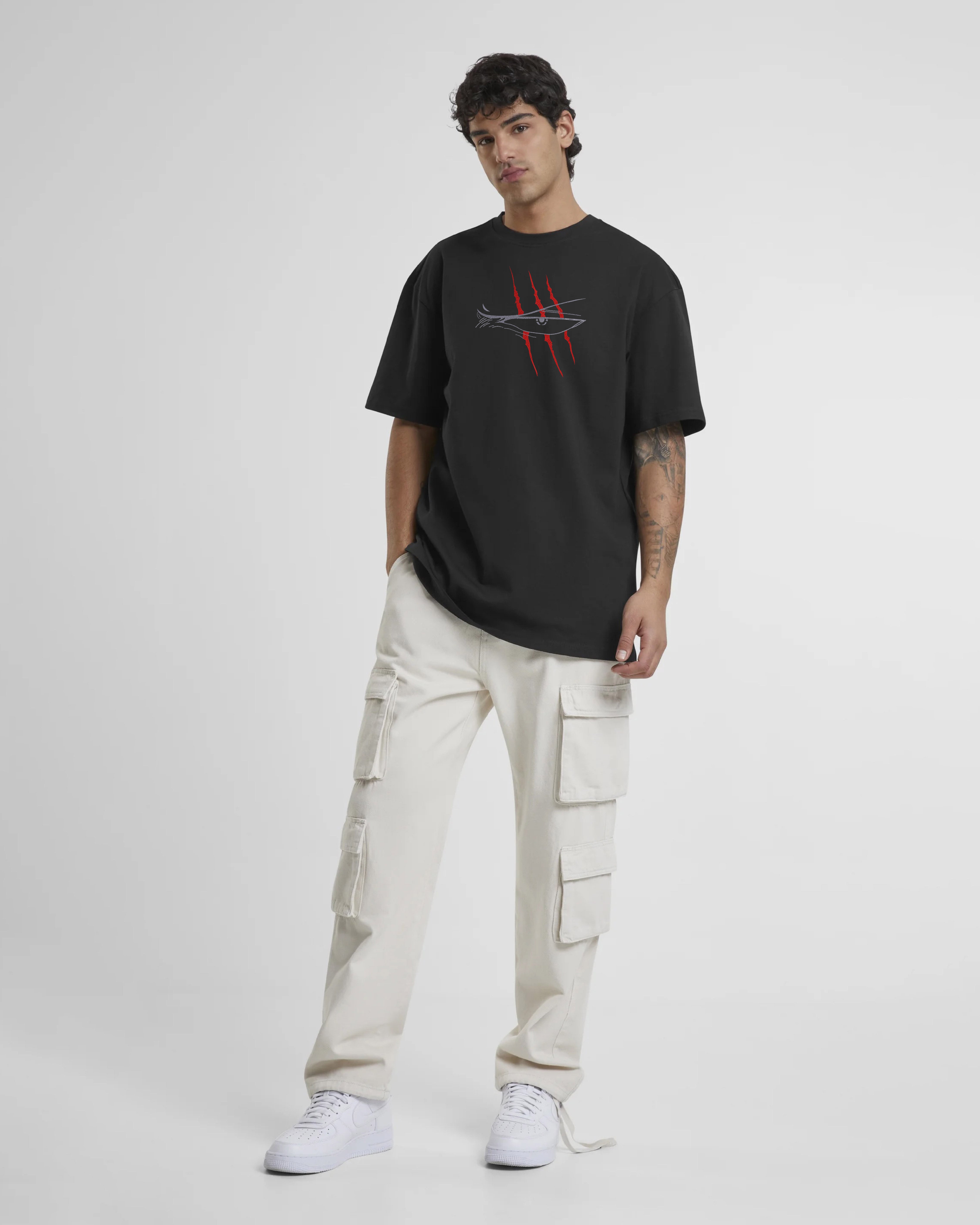 Person wearing a black t-shirt with a logo and beige cargo pants on a white background