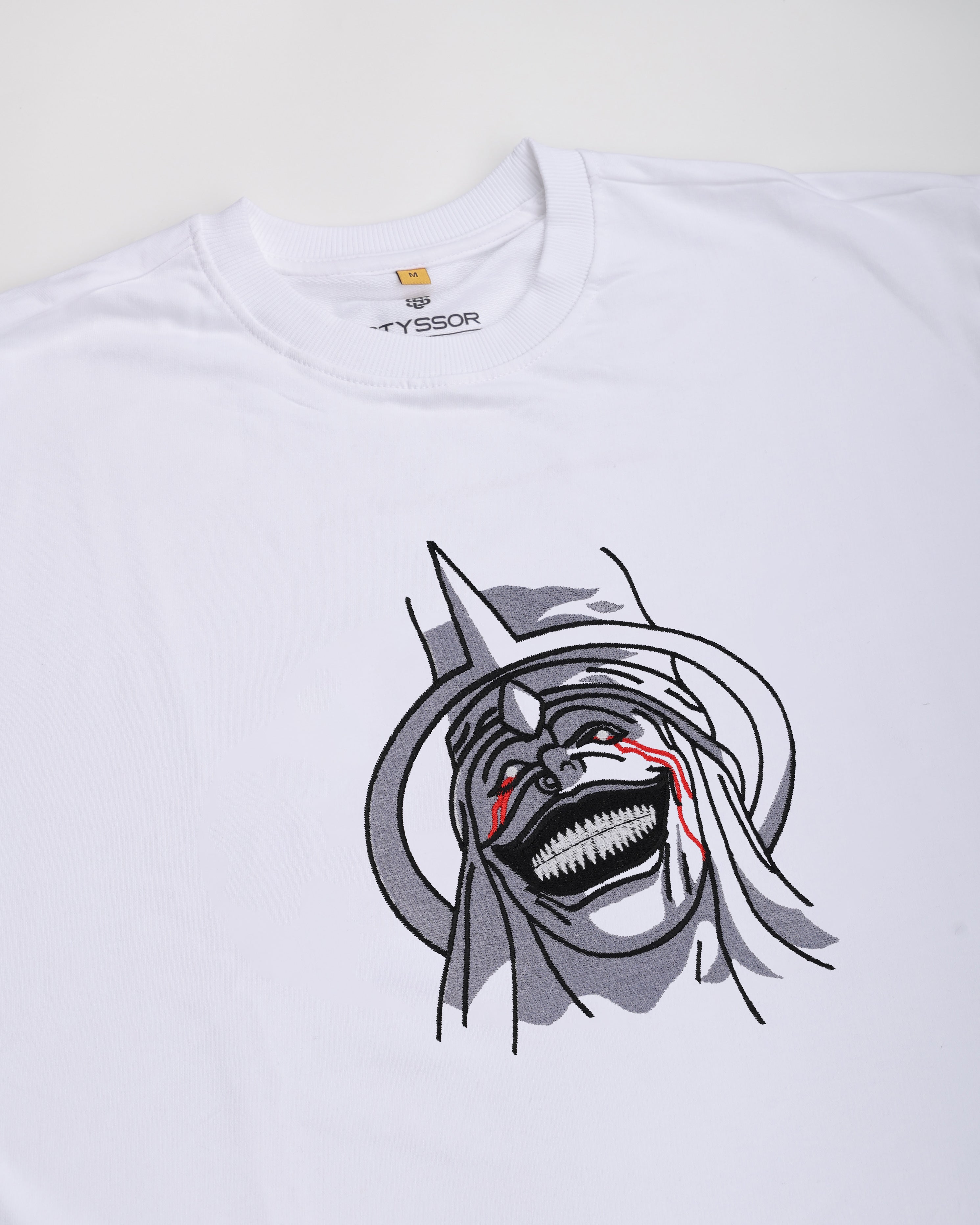White t-shirt with a graphic design of a character with a large mouth and red eyes on a white background.