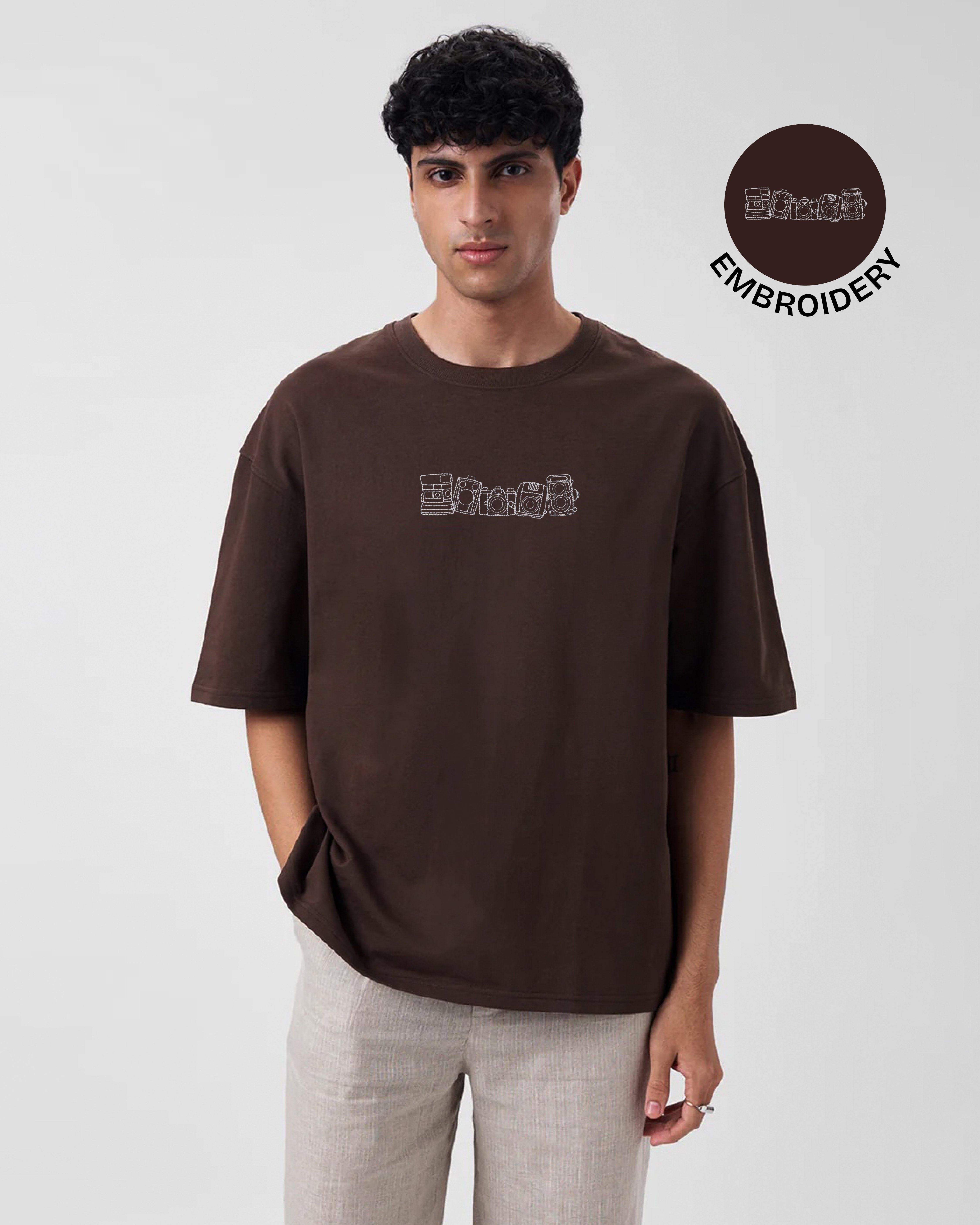 Man wearing a brown t-shirt with embroidery design on a white background